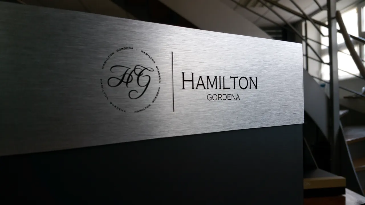 Enseigne professionnelle Hamilton Gordena — logo et nom gravés au laser sur plaque aluminium brossé